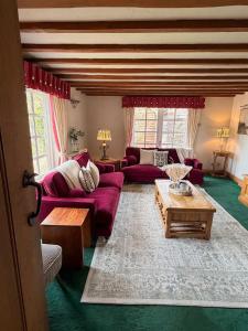 a living room with a red couch and a table at Mesopotamia Cottage in Clifton Hampden