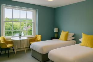 two beds in a room with a window and a table and chairs at The Lion Hotel in Builth Wells