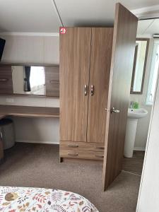 a bedroom with a large wooden cabinet and a sink at Swift Bordeaux 56 in Dunoon