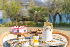 a table with a tea kettle and a cake and cookies at Luxury Ashok Cottage in Srinagar