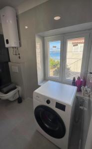 a washing machine in a kitchen with a window at apartment R in Mrljane