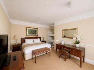 a hotel room with a bed and a desk and a television at Nent Hall Country House Hotel in Nenthead