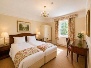 a bedroom with a large bed and a desk and a window at Nent Hall Country House Hotel in Nenthead