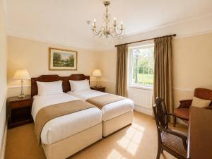 a bedroom with a bed and a window and a chandelier at Nent Hall Country House Hotel in Nenthead