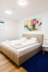 a large bed in a bedroom with a painting on the wall at KQC Boutique Villa in Balatonlelle