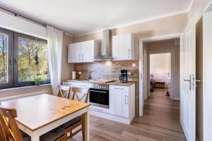a kitchen with white cabinets and a wooden table at Ferienwohnung Landblick in Brilon