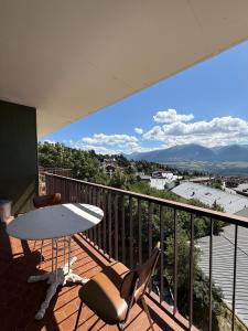 a balcony with a surfboard on a table and chairs at T3 hypercenter with fireplace, mountain view in Font-Romeu