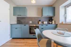 a kitchen with blue cabinets and a table with chairs at Gemütliche Ferienwohnung - Araliya 2 in Ahlbeck
