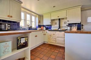 a kitchen with white cabinets and a tile floor at Martie Cottage - cosy cottage idyllic village in Whitcombe +14 photos