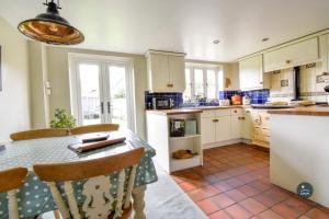a kitchen with a table and chairs and a kitchen with white cabinets at Martie Cottage - cosy cottage idyllic village in Whitcombe