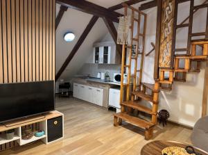 a living room with a tv and a wooden staircase at Baritiu Apartment Brasov in Braşov