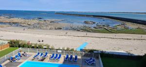a view of a beach with chairs and a swimming pool at Couleur océan, piscine et plage in Le Croisic