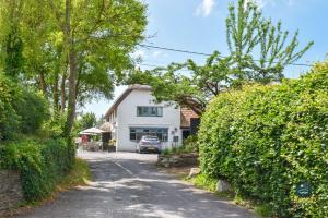 a white house with a car parked in a driveway at Martie Cottage - cosy cottage idyllic village in Whitcombe