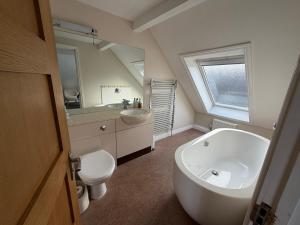 a bathroom with a tub and a toilet and a sink at Boathouse Hotel in Hythe +115 photos
