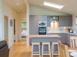 a kitchen with gray cabinets and a island with bar stools at Cedar Lodge in Hassocks +12 photos