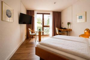 a hotel room with a bed and a table and a window at CityHotel Feuerbach in Stuttgart