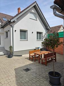 two benches and a table in front of a house at Harmónia Apartmanház in Kőszeg
