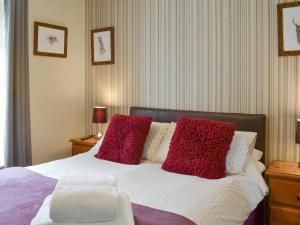 a bedroom with a bed with red and white pillows at Eldin Hall Cottage 2 - Uk2484 in Scarborough