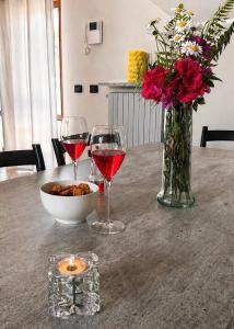 a table with two glasses of wine and a vase of flowers at Villa Motti Quadri in Arona