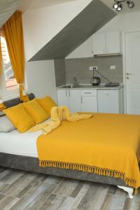 a bedroom with a bed with a yellow blanket on it at Apartmani Romansa in Irig