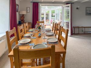 a long wooden table with chairs and plates on it at Prideaux Cottage in Par