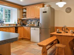 a kitchen with a stainless steel refrigerator and wooden cabinets at Prideaux Cottage in Par