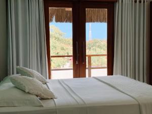 a bed with pillows and a window with a view at Pousada Jeri Dunas in Jericoacoara +36 photos