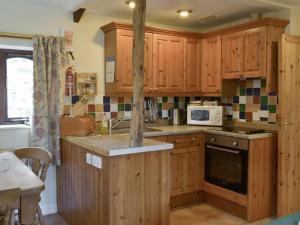 a kitchen with wooden cabinets and a stove top oven at Demelza in Launceston