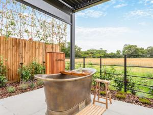 a metal tub on a patio with a view of a field at Uk47692 - Wiggles Cottage in Wimbish