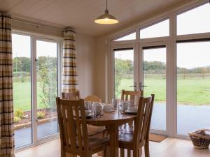 a dining room with a table and chairs and windows at Maple Lodge in Hassocks +8 photos