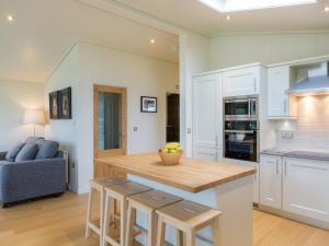 a kitchen with white cabinets and a wooden counter top at Maple Lodge in Hassocks