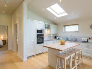 a kitchen with white cabinets and a kitchen island with bar stools at Maple Lodge in Hassocks