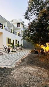 a white building with people sitting on benches in front of it at Chandan resort in Chitrāwal +6 photos