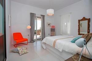 a white bedroom with a bed and a red chair at villa zakintos in Aspro Chorio Paros +11 photos
