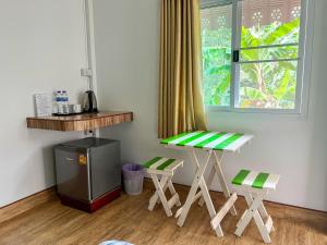 a room with a table and two stools and a window at Baan Suan Tondin in Ban Du Son