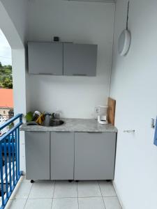 a kitchen with white cabinets and a sink at Chambres les pieds dans l’eau résidence Cypria in Les Trois-Îlets
