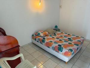 a bedroom with a bed and a chair in it at Chambres les pieds dans l’eau résidence Cypria in Les Trois-Îlets