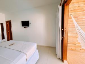 a bedroom with a bed and a tv on the wall at Pousada Jeri Dunas in Jericoacoara