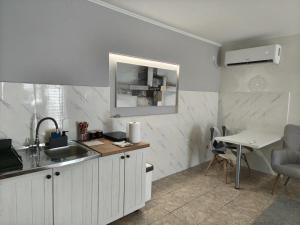a white kitchen with a sink and a table at Silver Spa Apartment in Bačka Palanka