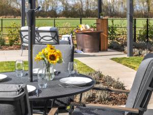 a table with a vase of sunflowers on a patio at Uk47693 - Piglet Cottage in Wimbish