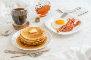 a table with plates of pancakes and a cup of coffee at Hotel Lords Inn in Lahore