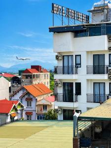 a building with red roofs and an airplane in the sky at Sunrise Airport Hotel Noi Bai in Noi Bai
