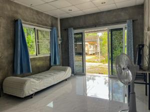 a living room with a couch and a fan at Baan Suan Tondin in Ban Du Son