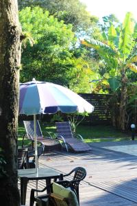 a table and chairs with an umbrella on a patio at Pousada Recanto Do Costão in Florianópolis