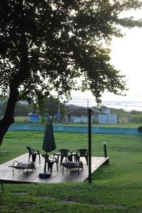a wooden deck with tables and chairs and an umbrella at Pousada Recanto Do Costão in Florianópolis