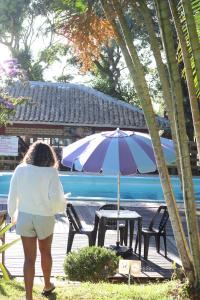 a woman walking past a table with an umbrella at Pousada Recanto Do Costão in Florianópolis