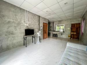 a living room with a bed and a table with a television at Baan Suan Tondin in Ban Du Son