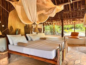 a bedroom with a large bed in a room with windows at Kwa Simba Tanzania in Pangani