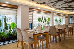 a dining room with tables and chairs and plants at Buyuk Velic Hotel in Gaziantep