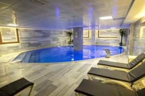 a large swimming pool in a room with chairs at Buyuk Velic Hotel in Gaziantep